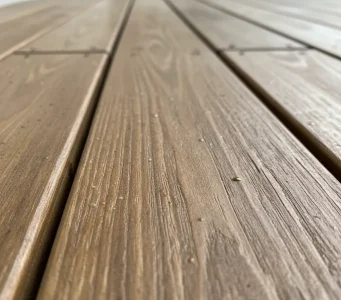 Close-up view of a freshly cleaned wooden deck in Orangevale, California, showing water droplets and natural wood grain from recent pressure washing services.