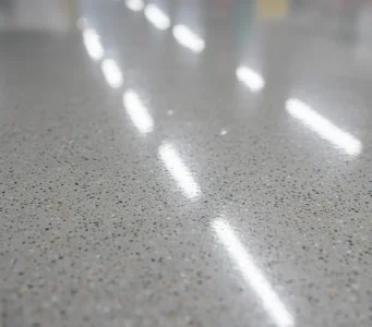 Clean and polished warehouse floor reflecting overhead lights, showcasing results of professional commercial pressure washing services in Sacramento